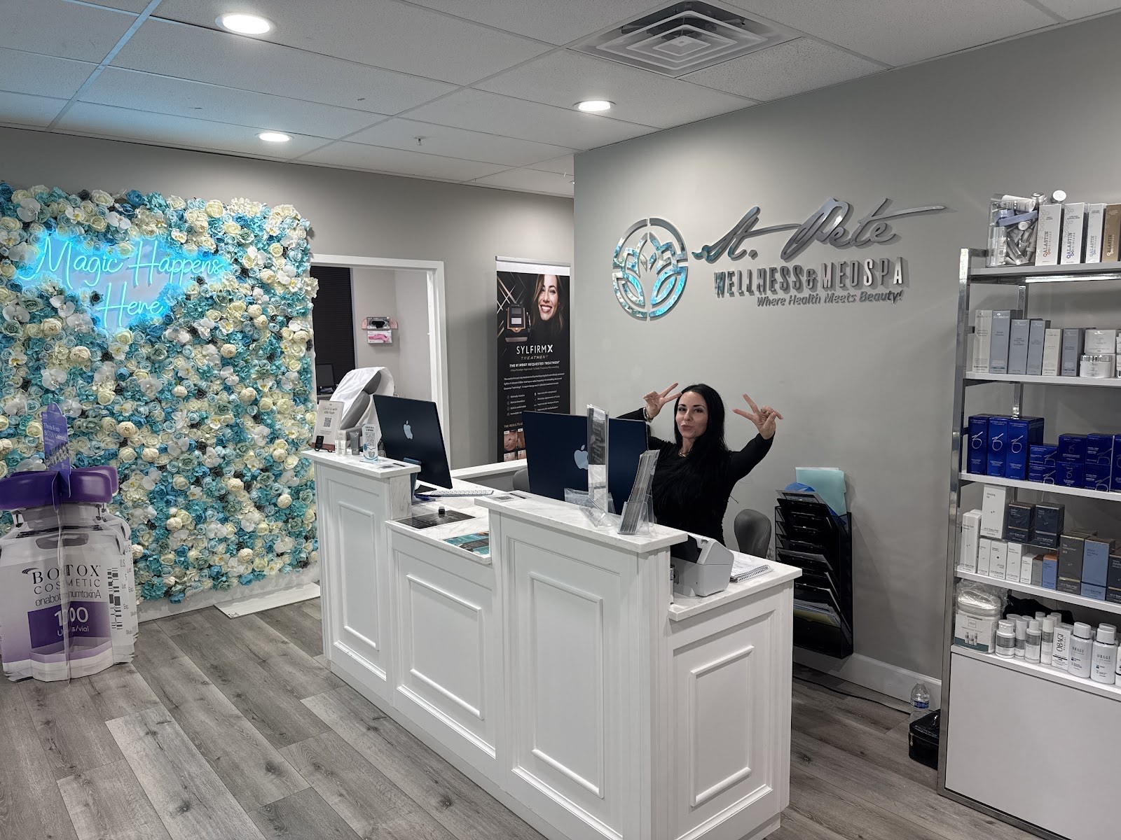 The bright St Pete Wellness Med Spa reception desk with the branded lotus logo and aqua floral wall
