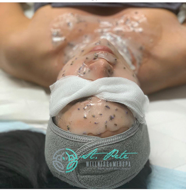 A client relaxing during a signature lavender facial treatment, branded with the St Pete Wellness Med Spa logo